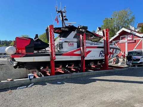 Hvit redningsbåt med røde detaljer i slipp